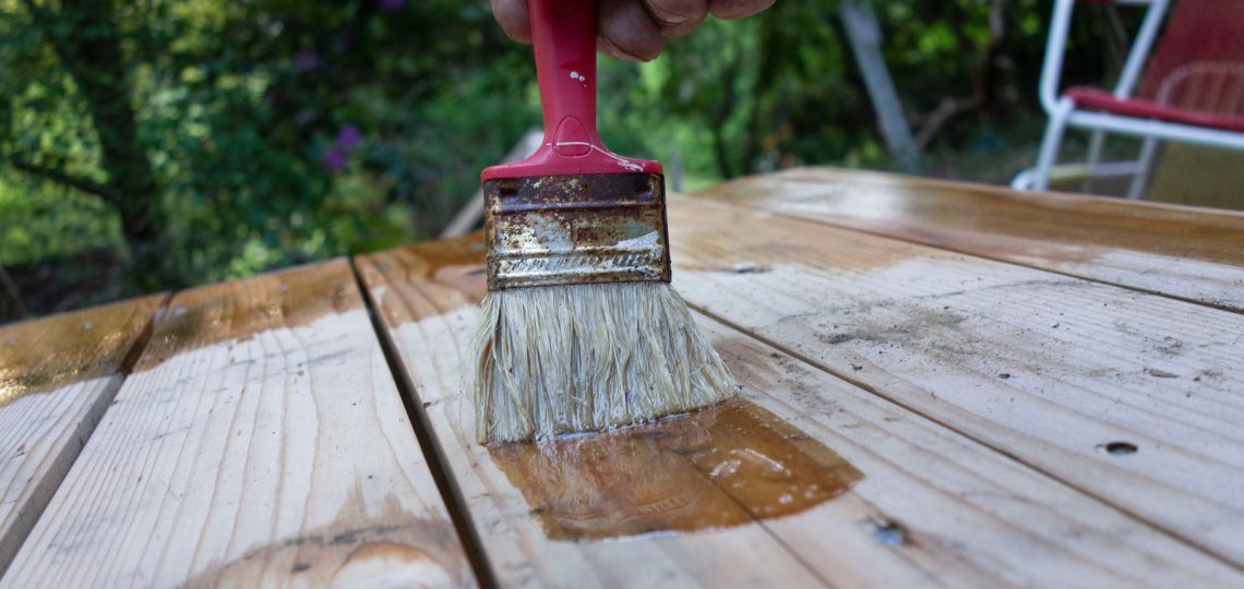 person brushing wood finish on wood