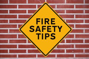 yellow sign stating fire safety tips on a brick background